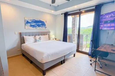 a bedroom with a bed and a desk and a window at Stylish 3-BR Vacation Condo with Scenic Rooftop in Jacó