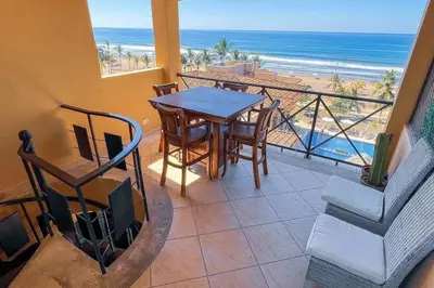 a balcony with a table and chairs and the beach at Stylish 3-BR Vacation Condo with Scenic Rooftop in Jacó