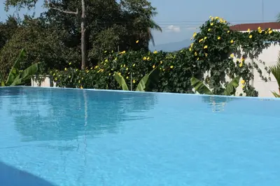 a blue swimming pool in front of a garden at Sol Pacifico Lodge in Cascajal