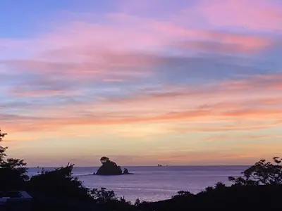 a sunset over the ocean with a rock in the water at Paseo Divino At Las Catalinas in Playa Danta