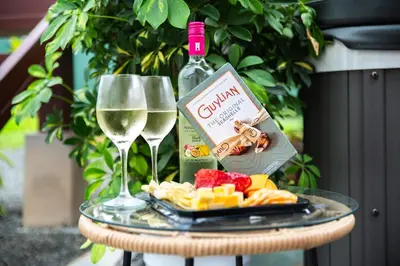 a glass table with a bottle of wine and wine glasses at House Monstera Arenal in Agua Azul