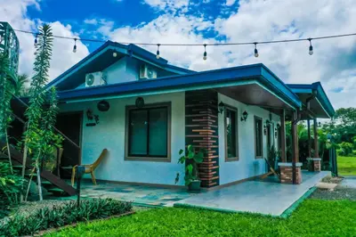 a small house with a blue roof at House Monstera Arenal in Agua Azul