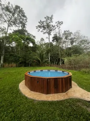 a circular pool in a field with trees in the background at Trailer House in Vara Blanca