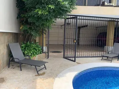 a fence with two chairs next to a swimming pool at Luxury House near to Juan Sant. Airport, Alajuela. in Alajuela City