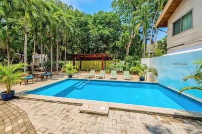 a swimming pool in a backyard with palm trees at Casa Corona Del Mar Tamarindo in Tamarindo