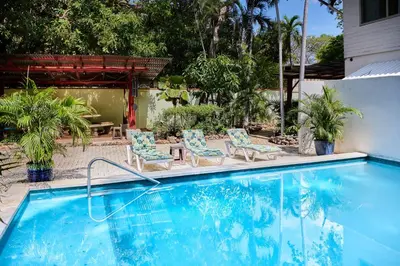 a swimming pool with two chairs and a table at Casa Corona Del Mar Tamarindo in Tamarindo