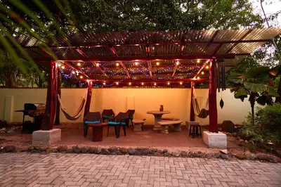 a patio with a table and chairs under a pergola with lights at Casa Corona Del Mar Tamarindo in Tamarindo