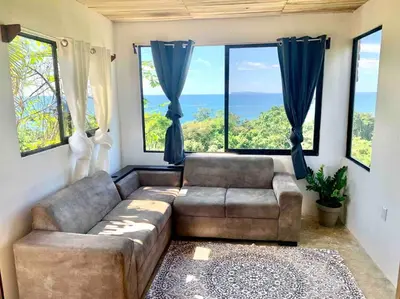 a living room with a couch and large windows at Cotinga Nest - King Bed, Ocean View in San Pedrillo
