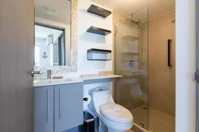 a bathroom with a toilet and a glass shower at Deluxe Apt with Ocean View & Beach Access only 1 hour drive from San Jose in Puntarenas