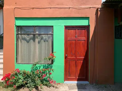 a green and red house with a red door and a window at Globi Lodge #6 in Monteverde Costa Rica