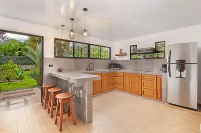 a kitchen with wooden cabinets and a stainless steel refrigerator at Casa Oasis La Fortuna Private Pool AC & WiFi 100 mbps in San Francisco