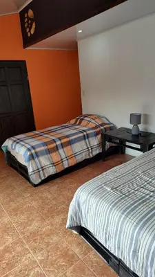 a bedroom with two beds and a table in it at Persea Inn & Restaurante Toro Careto in El Copey