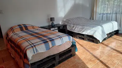 two twin beds in a room with a night stand and a table at Persea Inn & Restaurante Toro Careto in El Copey