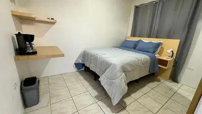 a small bedroom with a bed with blue pillows at Nomada Monteverde in Monteverde Costa Rica