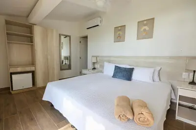 a bedroom with a white bed with two towels on it at Perla de la Playa Beachfront Hotel in Tamarindo