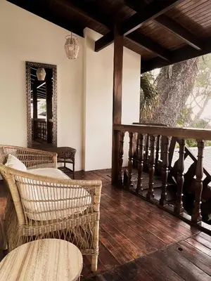 a porch with wicker chairs and a wooden floor at Perla de la Playa Beachfront Hotel in Tamarindo