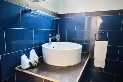 a bathroom with a sink and blue tiled walls at Perla de la Playa Beachfront Hotel in Tamarindo