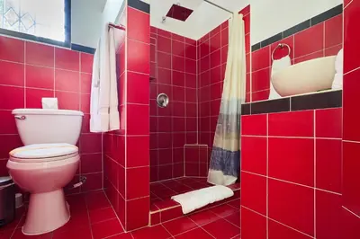 a red tiled bathroom with a toilet and a shower at Perla de la Playa Beachfront Hotel in Tamarindo
