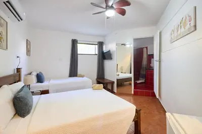 a bedroom with two beds and a ceiling fan at Perla de la Playa Beachfront Hotel in Tamarindo