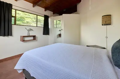 a bedroom with a white bed and a window at Perla de la Playa Beachfront Hotel in Tamarindo