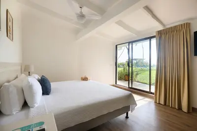 a bedroom with a bed and a large window at Perla de la Playa Beachfront Hotel in Tamarindo