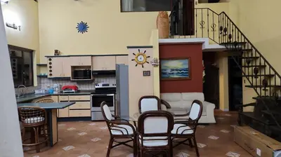 a kitchen with chairs and a table and a refrigerator at CASA DE PLAYA CON PISCINA EN PUNTA LEONA in Puntarenas