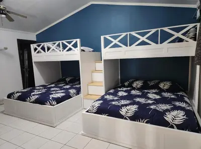 a bedroom with two bunk beds and a blue wall at CASA DE PLAYA CON PISCINA EN PUNTA LEONA in Puntarenas