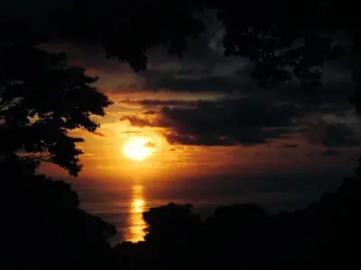 a sunset over the ocean with the sun in the sky at Tree of Life Cabinas in Dominical