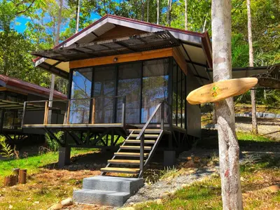 a house in the woods with a surfboard on a tree at The Elements Costa Rica Nature Lodges in Platanillo