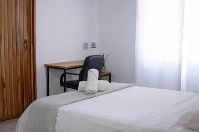 a bedroom with a bed with a chair and a desk at Leidy Mar Apartments in Santa Teresa Beach