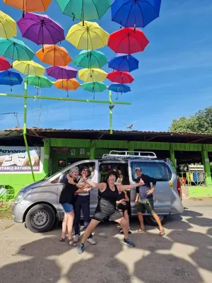 a group of people standing in front of a van with umbrellas at Chilamate Room in Tortuguero