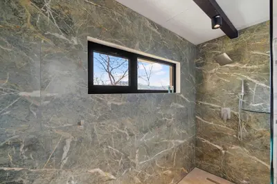 a bathroom with a stone wall and a window at Nostalgic Retro Home on Luxurious Lot with a Private Infinity Pool and Ocean Views in Santa Cruz