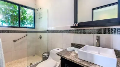 a bathroom with a sink and a shower and a toilet at Nostalgic Retro Home on Luxurious Lot with a Private Infinity Pool and Ocean Views in Santa Cruz