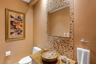 a bathroom with a sink and a toilet and a mirror at Stunning Luxury Penthouse in Exclusive Beachfront Community with Resort-Style Amenities & Sweeping Views of the Ocean & Golf Course in Santa Cruz