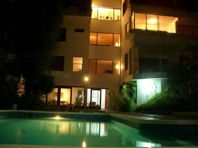 a building with a swimming pool in front of a building at night at Hermosa Habitación privada en la Sabana, San Jose in San José