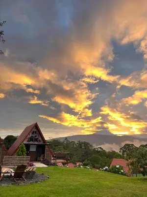 a cloudy sky with a house in a field at Chalets Vistas del Poas in Heredia