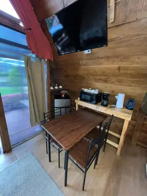 a wooden table with chairs and a television on a wall at Chalets Vistas del Poas in Heredia