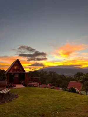 a cabin on a hill with a sunset in the background at Chalets Vistas del Poas in Heredia