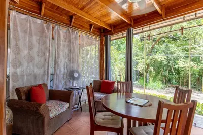 a dining room with a table and chairs and a large window at Cozy Beach Casita - 4 Min Walk to the Beach in Nosara