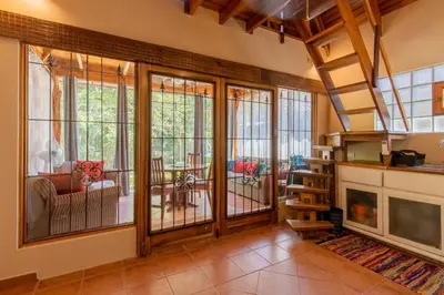 a living room with large windows and a staircase at Cozy Beach Casita - 4 Min Walk to the Beach in Nosara