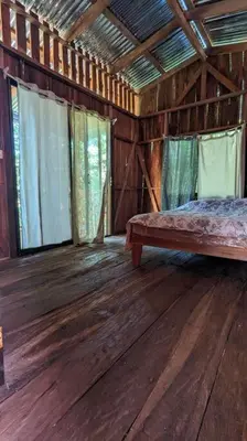 a bedroom in a wooden cabin with a bed and windows at Landscape-Cabaña Summer-Full Equipada in La Cruz