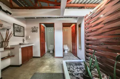 a bathroom with two toilets and a wooden wall at Pipe House Playa Grande in Playa Grande