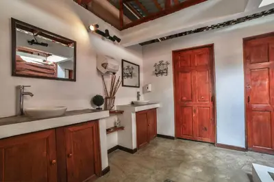 a bathroom with a sink and a mirror and a door at Pipe House Playa Grande in Playa Grande