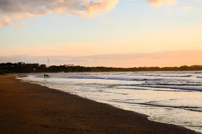 a person walking on the beach at sunset at Pipe House Playa Grande in Playa Grande