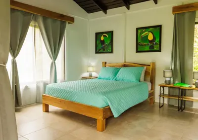 a bedroom with a bed with a blue comforter at Villa El Tucán in Bijagua