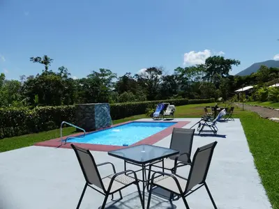a patio with a table and chairs next to a swimming pool at Villa El Tucán in Bijagua