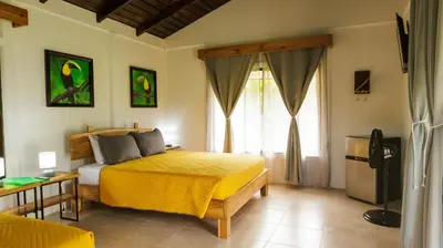 a bedroom with a bed with a yellow bedspread at Villa El Tucán in Bijagua
