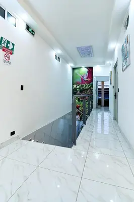 a hallway with white marble floors and a wall with a painting at Apartaestudios La capital in San José