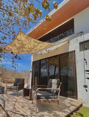 two chairs sitting on a patio outside of a house at Cozy Cottage Hilltop near Conchal - Casa Vala in Matapalo