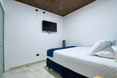 a bedroom with a bed with a tv on the wall at APARTAMENTO LA CAPITAL in San José
